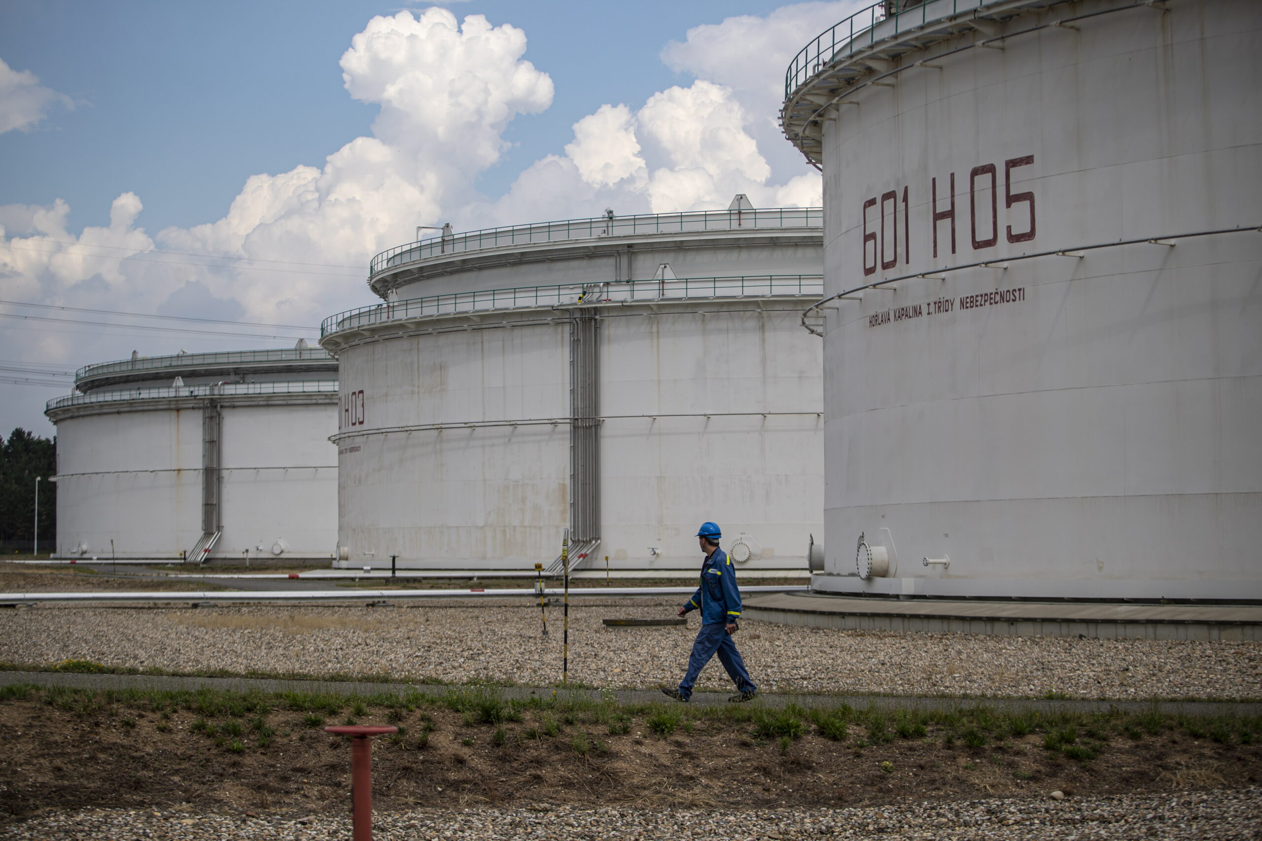 An employee walks past storage tanks at the Central oil tank farm operated by Mero CR near Nelahozeves, Czech Republic, 15 August 2022. Mero CR owns and operates the Czech part of the Druzhba pipeline and the IKL pipeline, is the sole transporter of crude oil to the Czech Republic, and also provides storage for the Czech emergency strategic oil reserves. Both pipelines enter the Central oil tank farm near Nelahozeves, where the company has built a total of 17 oil tanks with a total storage capacity of 1 675 000 m3. In June 2022, the European Union approved a sixth package of sanctions over Russia's invasion of Ukraine, which includes a ban on most Russian oil imports from the turn of the year. Oil transport via the Druzhba pipeline supplying the Czech Republic, Slovakia and Hungary will be temporarily excluded from the embargo.