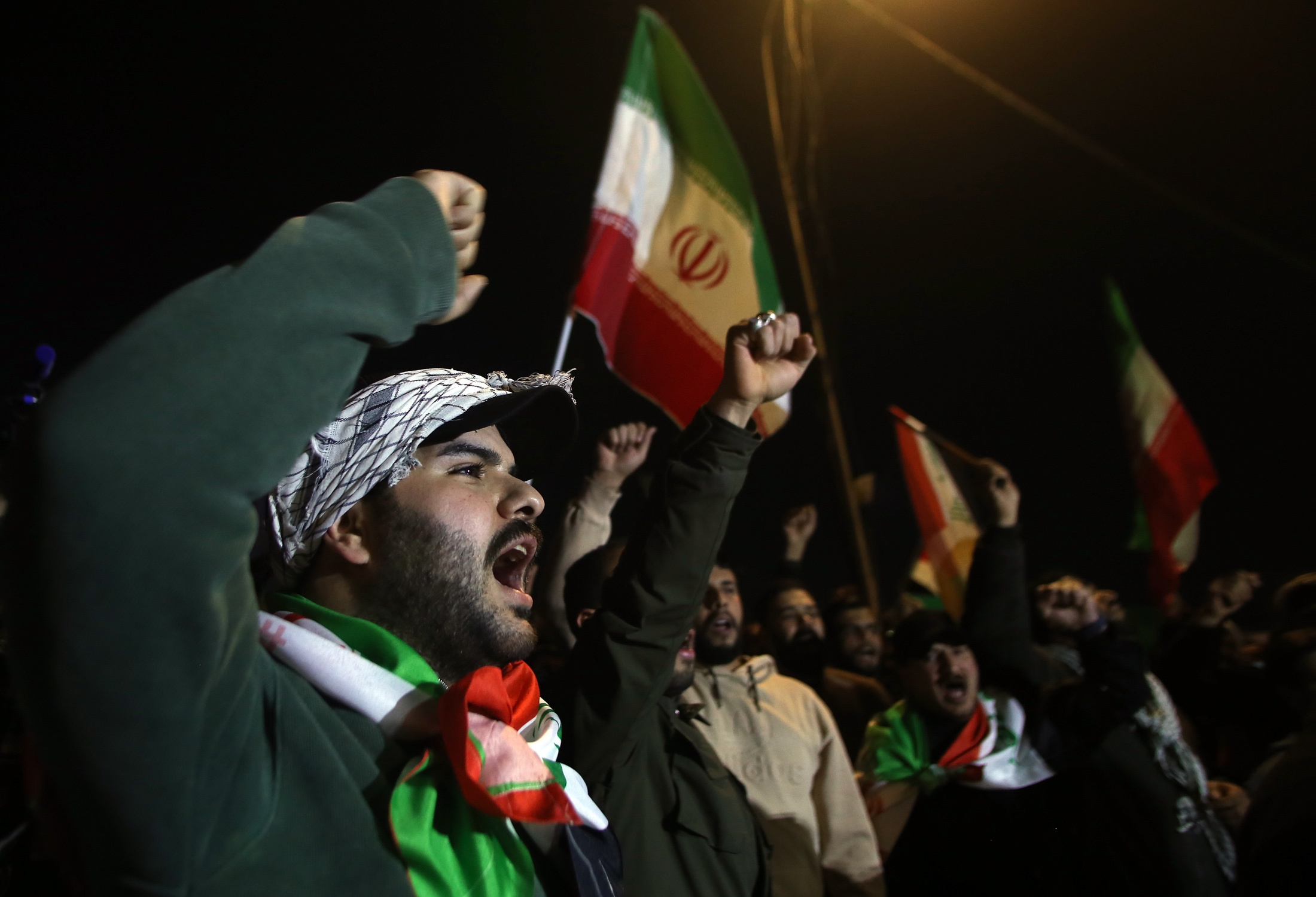 Protesters hold Iranian flags and portraits of Irans supreme leader Ayatollah Ali Khamenei during a protest against US and Israeli attacks on multiple cities across Iran; at a bridge leading to the fortified Green Zone where the US Embassy is located in Baghdad, Iraq, 28 February 2026.