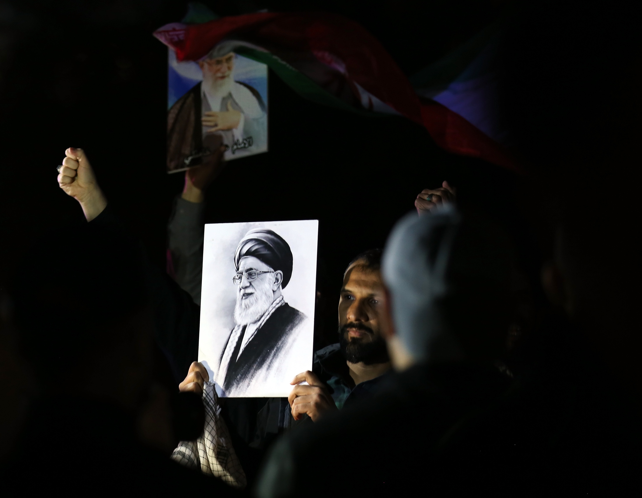 Protesters hold Iranian flags and portraits of Irans supreme leader Ayatollah Ali Khamenei during a protest against US and Israeli attacks on multiple cities across Iran; at a bridge leading to the fortified Green Zone where the US Embassy is located in Baghdad, Iraq, 28 February 2026.
