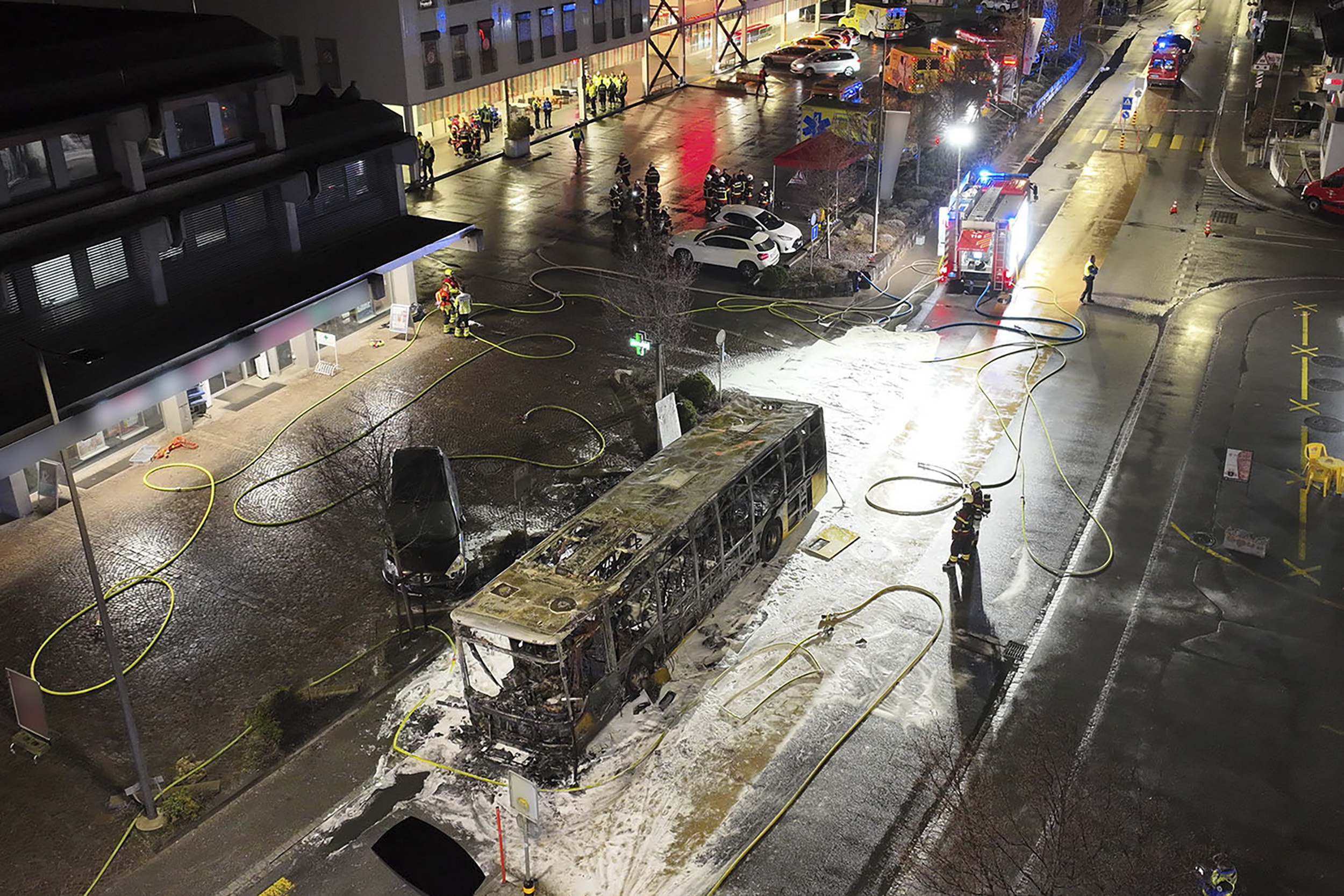 A handout photo taken with a drone made available by the Fribourg cantonal police shows fire investigators examining the charred shell of a postal bus after it caught fire in Kerzers, Switzerland, 10 March 2026. According to Fribourg cantonal police, several passengers were killed and others were injured when the postal bus caught fire in Kerzers.