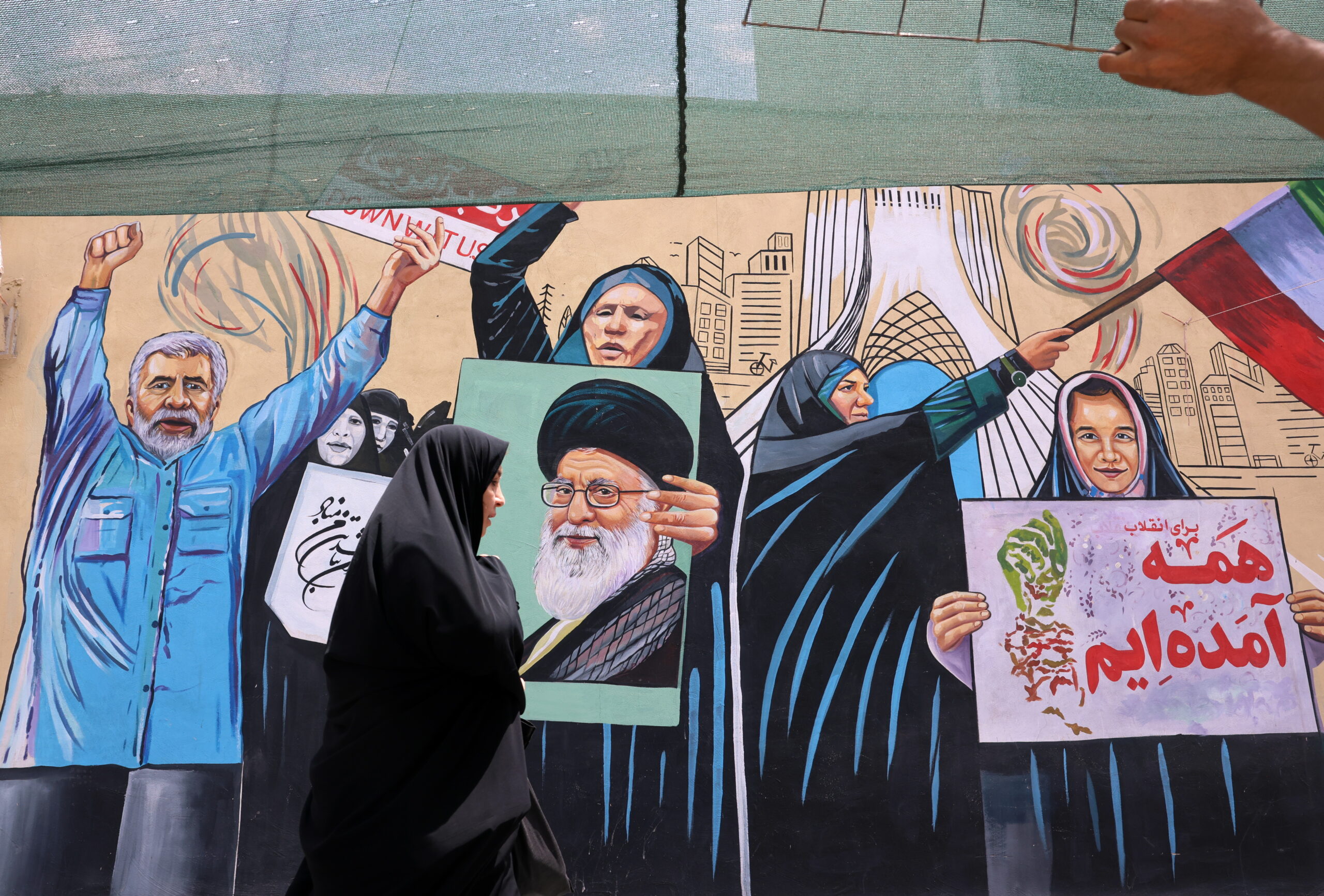 A woman walks next to anti-US wall painting on a street in Tehran, Iran, 20 July 2026. The US continued strikes against Iran for the ninth consecutive night on 19 July targeting 'military command centers, air defense and coastal surveillance sites, maritime capabilities, missile and drone launch sites', the US Central Command (CENTCOM) announced, amid the continuing conflict between Iran and US over the Strait of Hormuz.