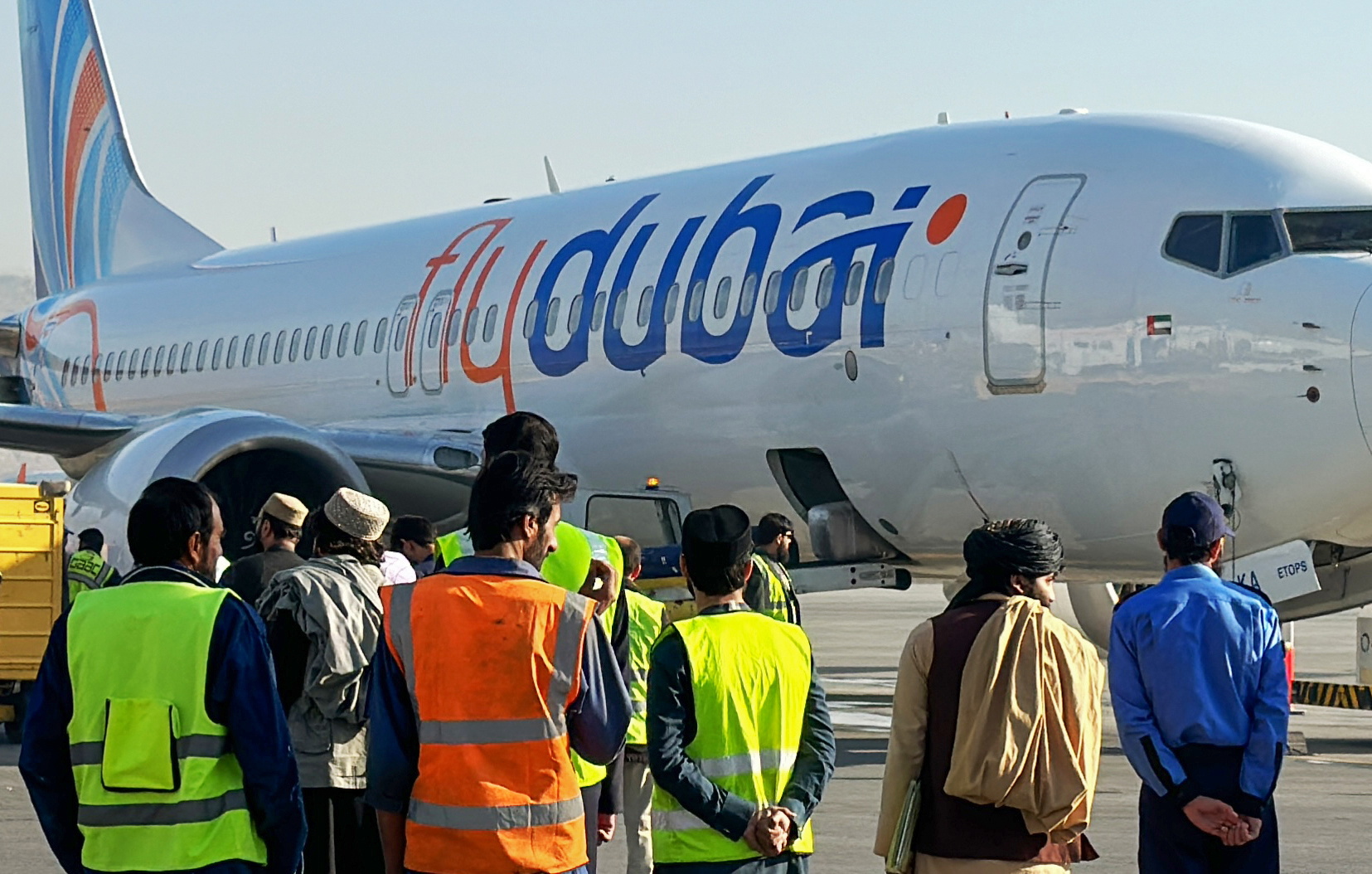 epa10976247 People stand next to a flydubai plane after it landed at Kabul airport in Kabul, Afghanistan, 15 November 2023. Flydubai resumed flights to Kabul International Airport after a two-year suspension, following the airline's October announcement to reinstate flights between the UAE and Kabul, signaling a positive step in restoring air connectivity.