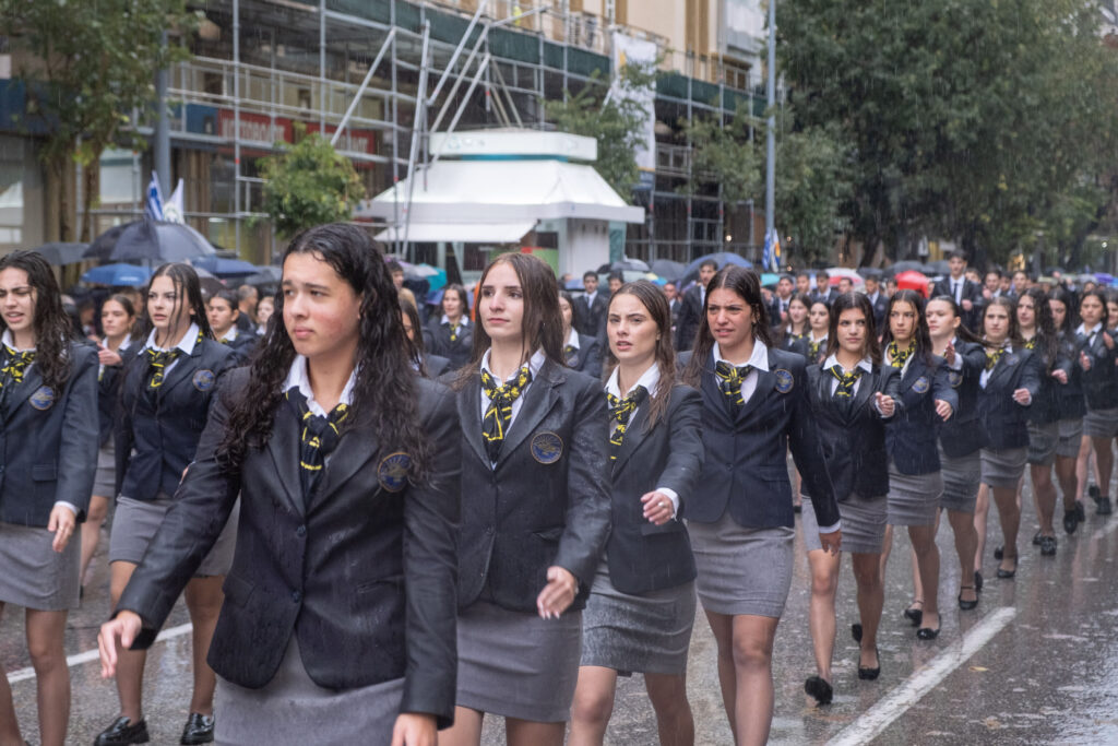 Μαθητές και μαθήτριες, από όλες της βαθμίδες της εκπαίδευσης, παρελαύνουν στη μαθητική παρέλαση για την 28η Οκτωβρίου, Θεσσαλονίκη, Δευτέρα 27 Οκτωβρίου 2025. Υπό καταρρακτώδη βροχή πραγματοποιήθηκε φέτος η μαθητική παρέλαση για την επέτειο της 28ης Οκτωβρίου στο κέντρο της Θεσσαλονίκης. Λόγω των ιδιαίτερα δύσκολων καιρικών συνθηκών, υπήρξε μία μικρή καθυστέρηση στην έναρξη της παρέλασης αλλά τελικά αποφασίστηκε οι μαθητές να παρελάσουν κανονικά. Την παρέλαση παρακολούθησαν από την εξέδρα των επισήμων: ο Μητροπολίτης Θεσσαλονίκης, Φιλόθεος, οι υφυπουργοί Εσωτερικών (αρμόδιος για θέματα Μακεδονίας και Θράκης), Κωνσταντίνος Γκιουλέκας, Παιδείας, Θρησκευμάτων και Αθλητισμού, Νίκος Παπαϊωάννου, Ανάπτυξης, Σταύρος Καλαφάτης, Κοινωνικής Συνοχής Και Οικογένειας, Έλενα Ράπτη, ο Αντιπεριφερειάρχης Θεσσαλονίκης, Κώστας Γιουτίκας, κ.ά.