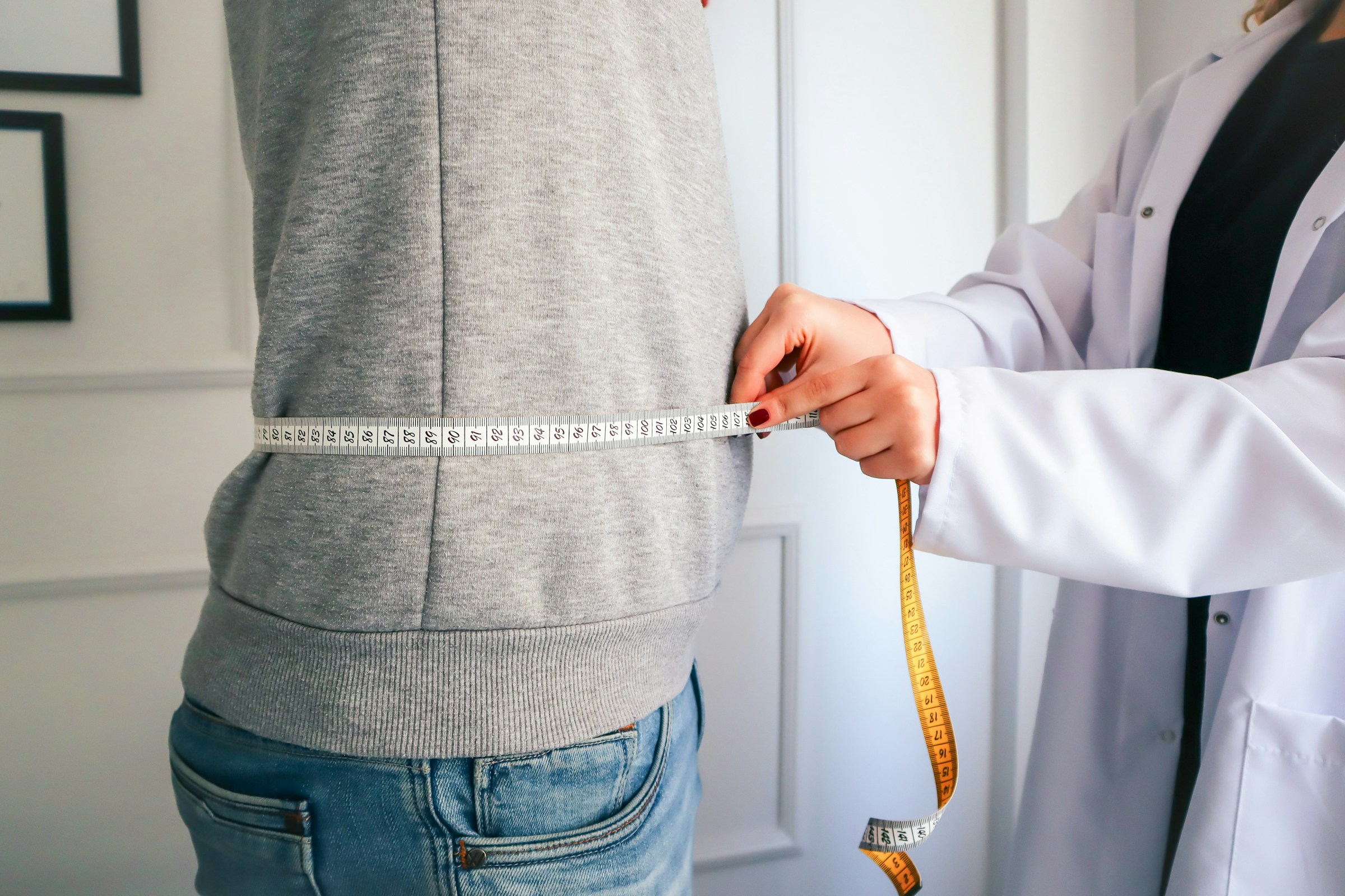 a woman measuring her waist with a measuring tape