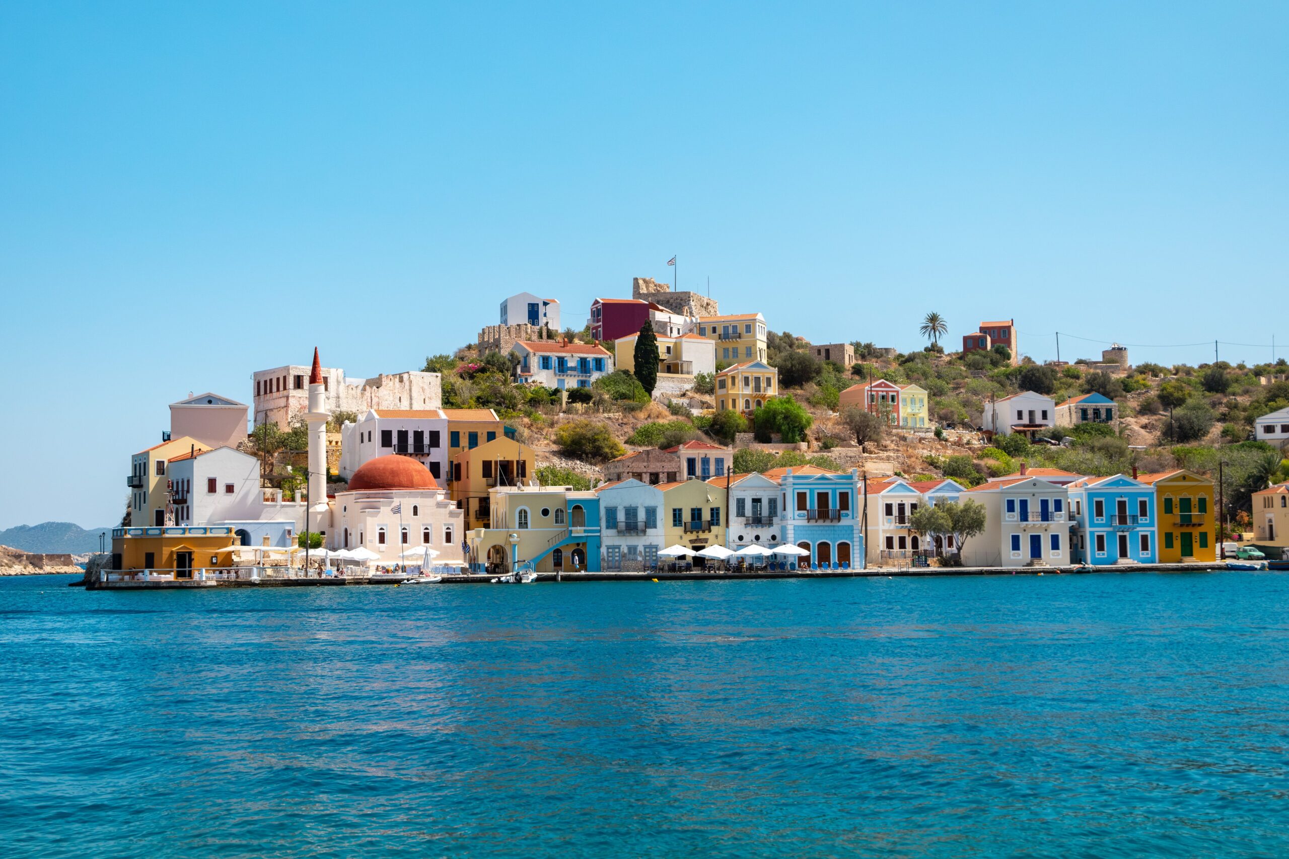 Vibrant waterfront buildings in Kastellorizo, Greece with blue seas and clear skies.