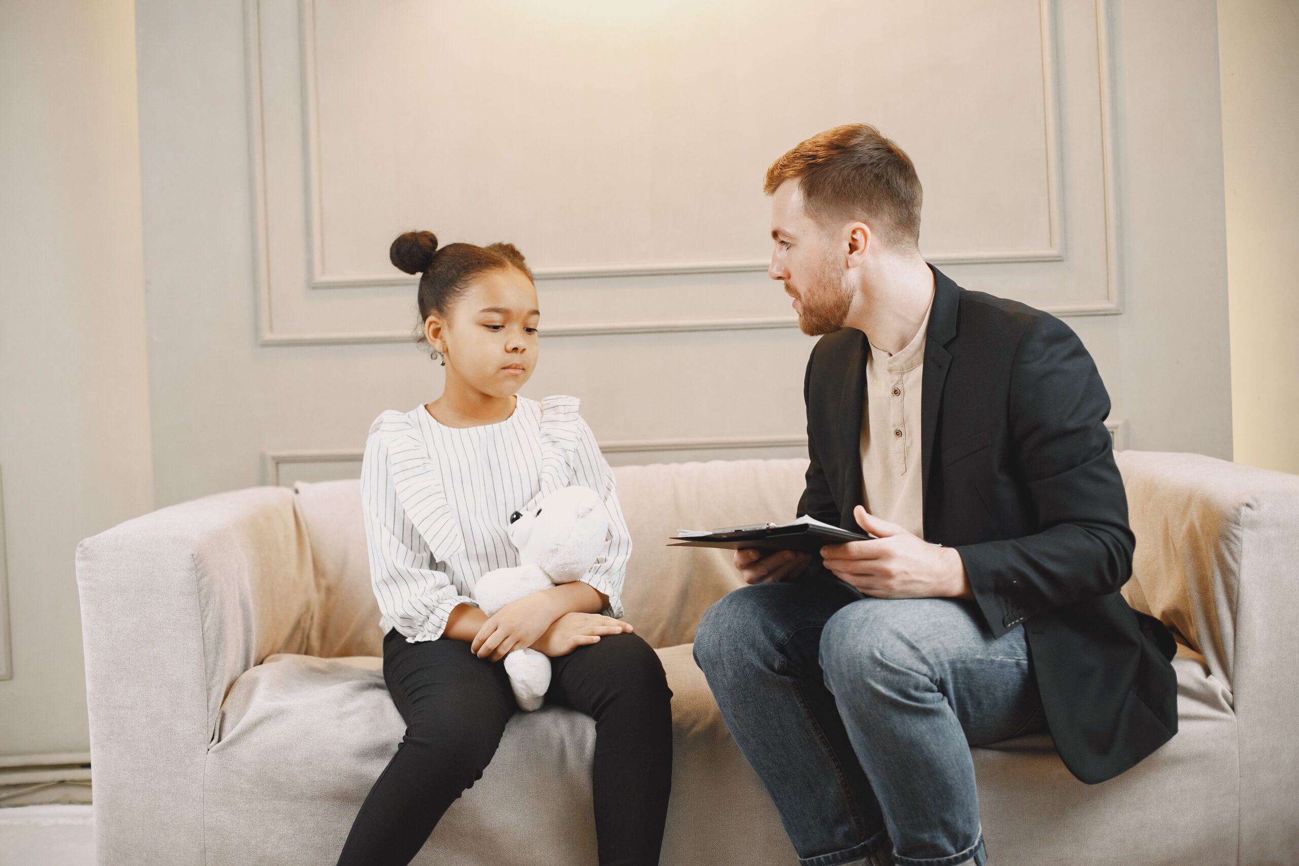 A young girl and a counselor having a therapy session indoors, fostering emotional support.
