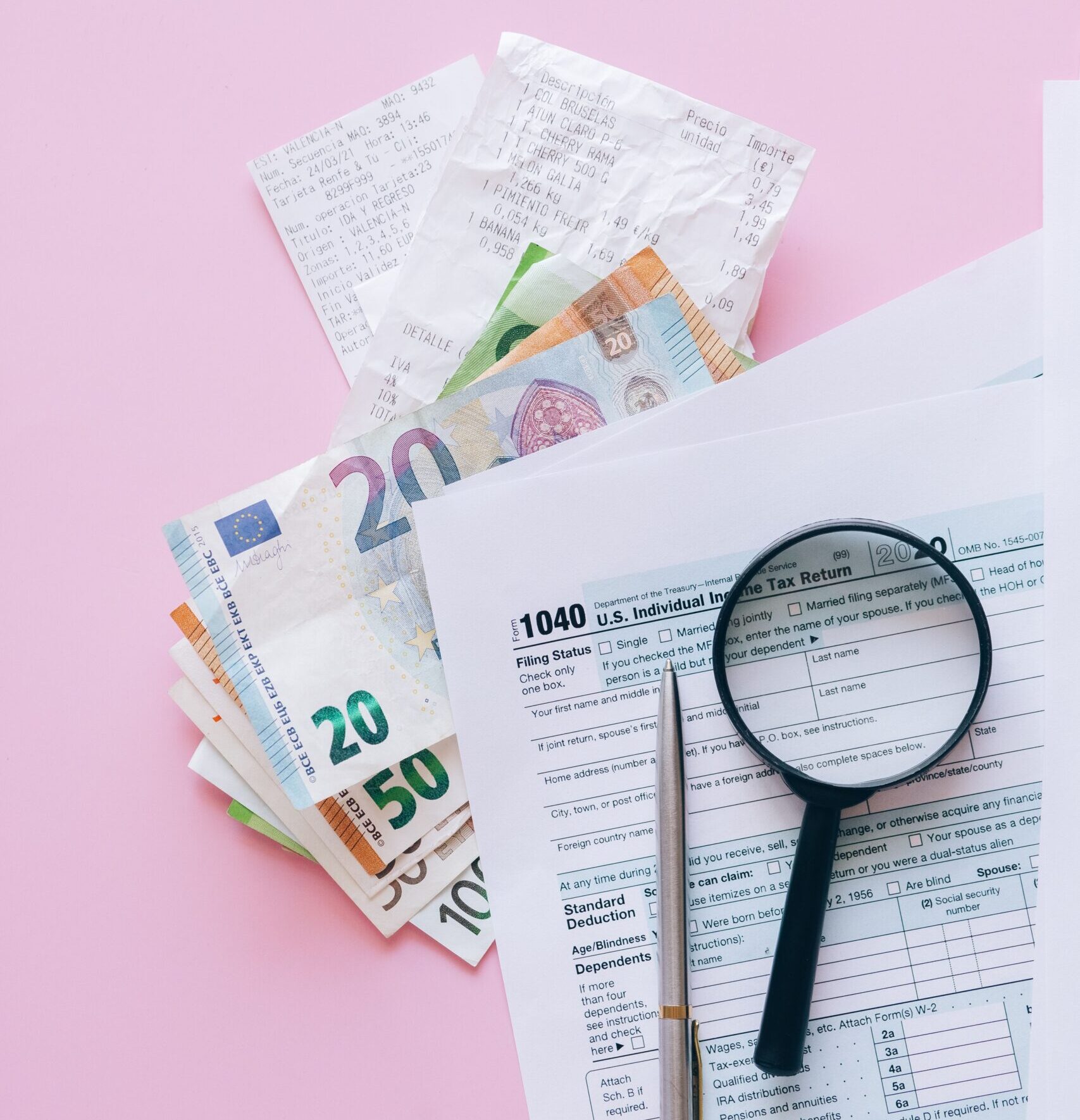 A collection of financial papers, including euro notes, tax return forms, and receipts on a pink surface.